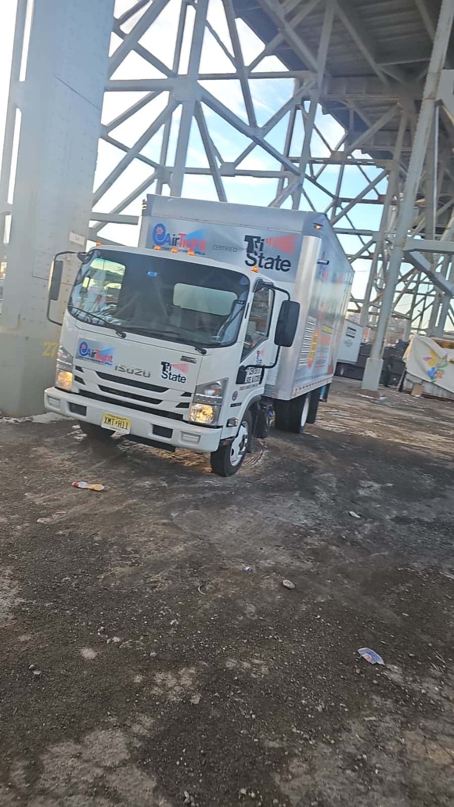 Tri State commercial spray foam insulation truck parked at a commercial job site under a steel bridge structure