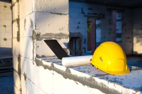 Hard hat and building plans on a block wall at an insulation project site